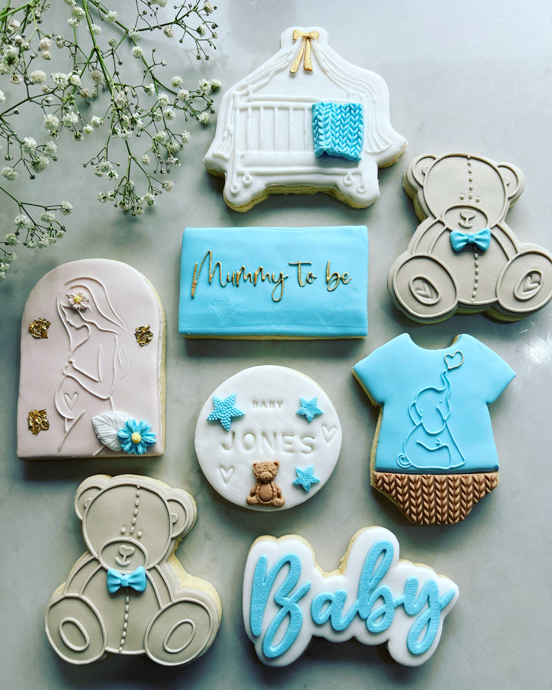 Blue boy baby shower cookies with rectangle mummy to be cookie.  Pink Pregnant mother Arch Cookie above Brown Bear cookie and Baby Stamp Cookie 